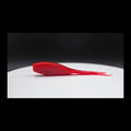 Red fishing lure with black glitter on a white surface with a dark background