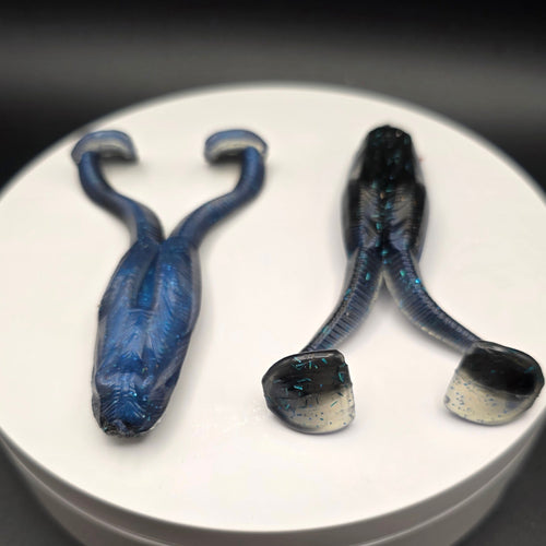 Black and Blue fishing lures with blue glitter on a white circular base against a dark background